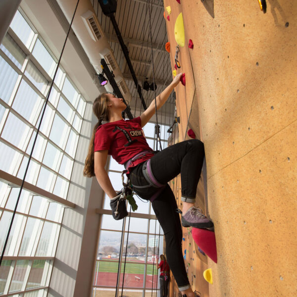 a student scales the climbing wall