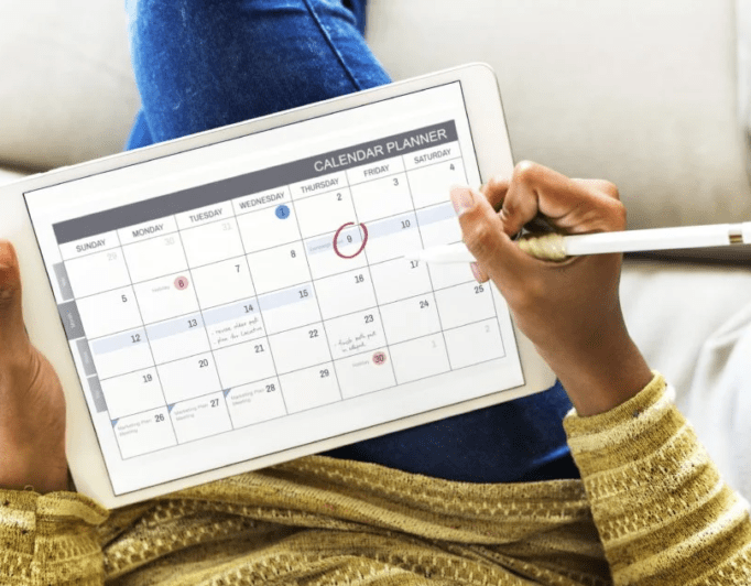 someone working with a calendar on their tablet
